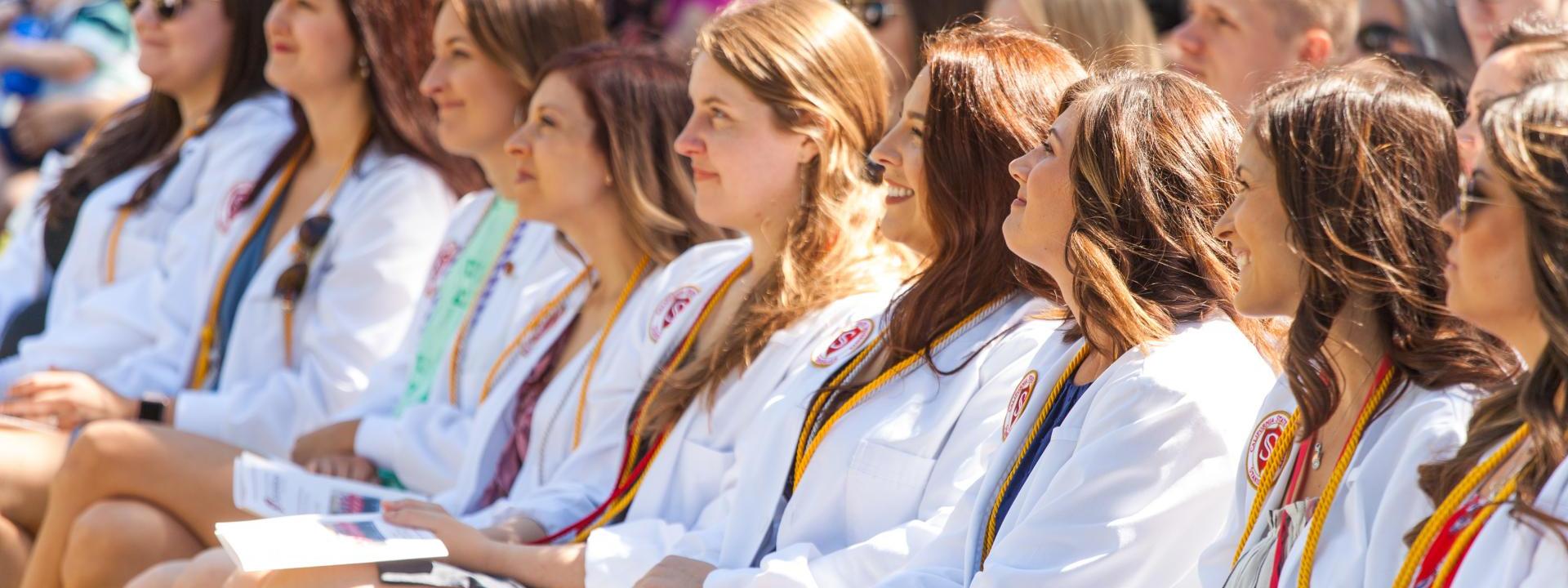 Graduates sitting wearing white coats