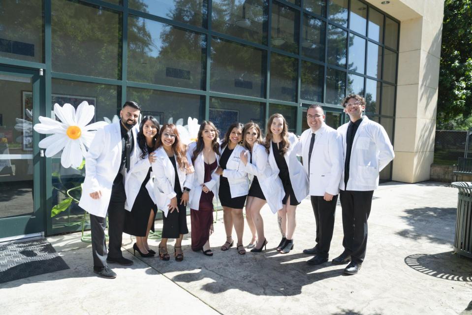 Nursing Students Graduates standing in front of building in white coats.