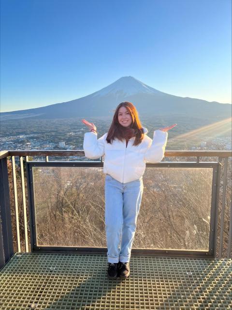 Person on a viewing platform with a snow-capped mountain in the background.
