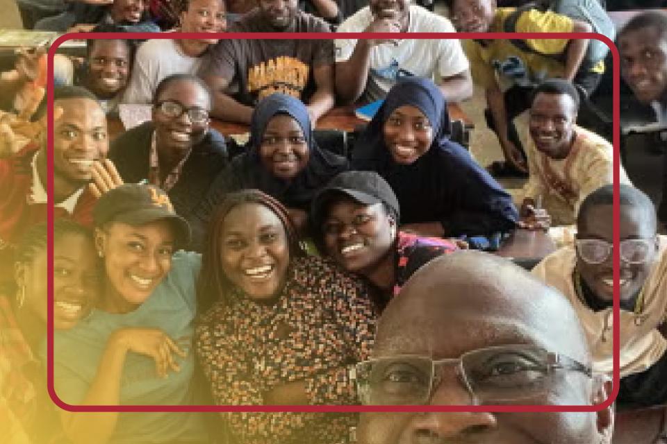 A Professor taking a selfie with a group of students behind him.